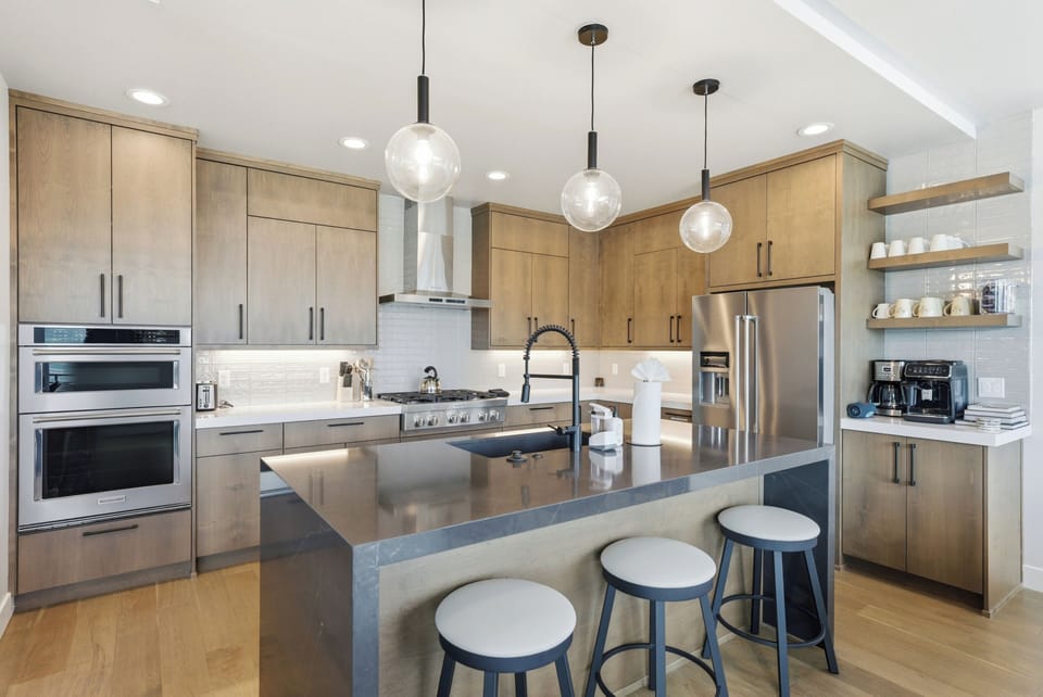 Cook with ease in the modern kitchen, featuring premium appliances, a spacious island, and seating for three. (Serenity Now)