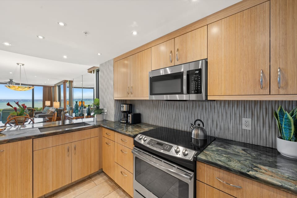Cook with a view in the fully equipped kitchen, complete with stainless steel appliances, custom cabinetry, and a wide breakfast bar overlooking the living area.