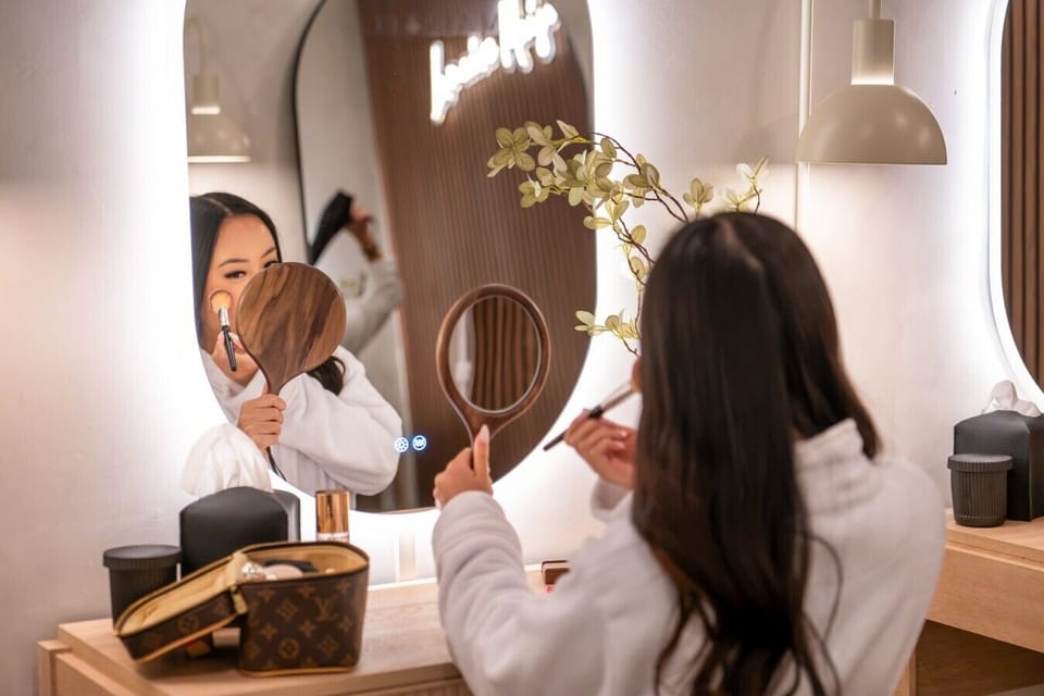 A guest getting ready at the vanity mirror surrounded by fresh florals.