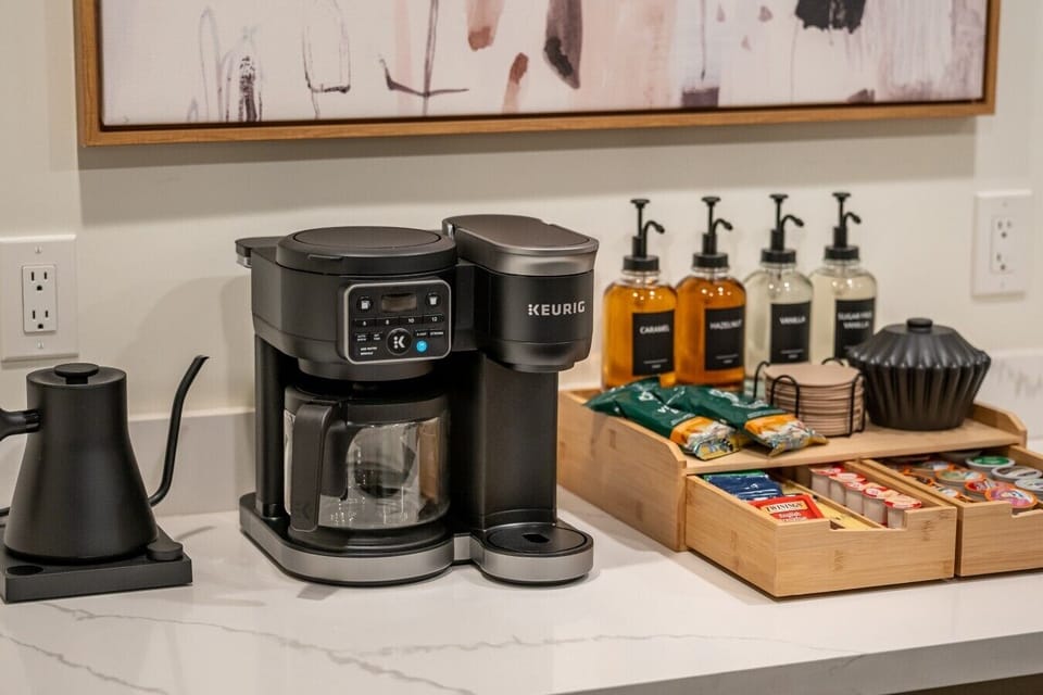 A coffee and beverage station stocked with a Keurig, mixers, and snacks.