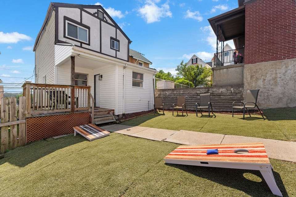 Private turf backyard with deck seating and cornhole fun