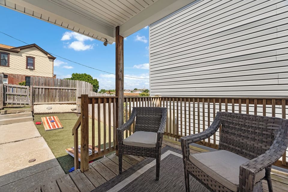 Covered porch with cozy seating and fenced yard with cornhole