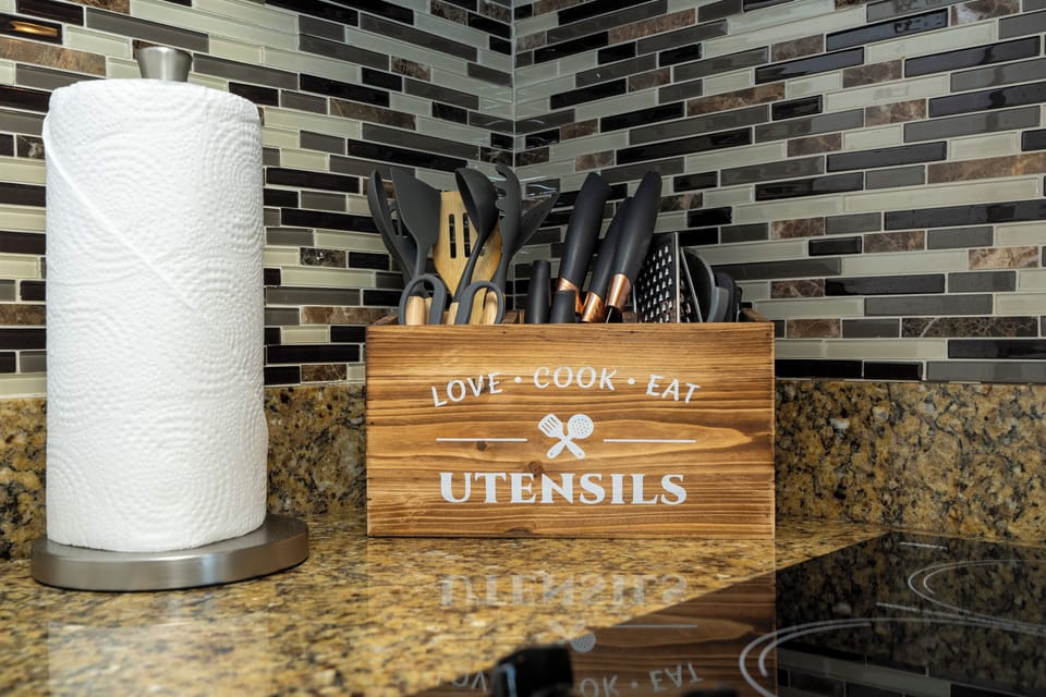 Cook with ease in a stylish, fully equipped kitchenette designed for comfort and convenience. Featuring modern cabinetry, a cooktop, microwave, dishwasher, mini fridge, sink, coffee maker, cookware, dishes, glasses, utensils, and ample counter space.