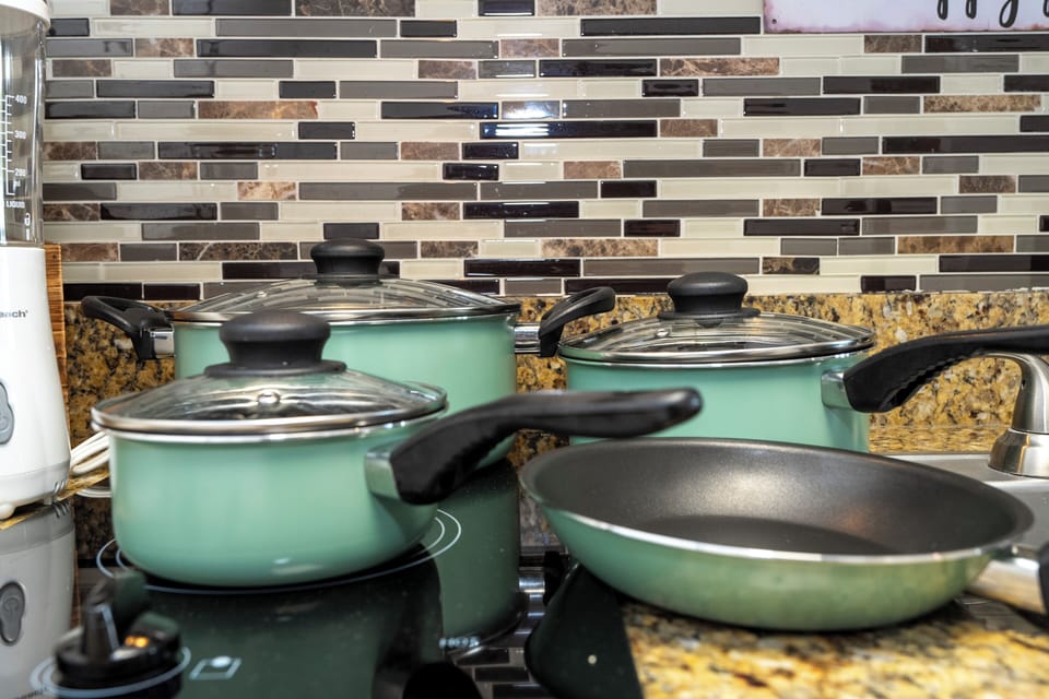 Cook with ease in a stylish, fully equipped kitchenette designed for comfort and convenience. Featuring modern cabinetry, a cooktop, microwave, dishwasher, mini fridge, sink, coffee maker, cookware, dishes, glasses, utensils, and ample counter space.
