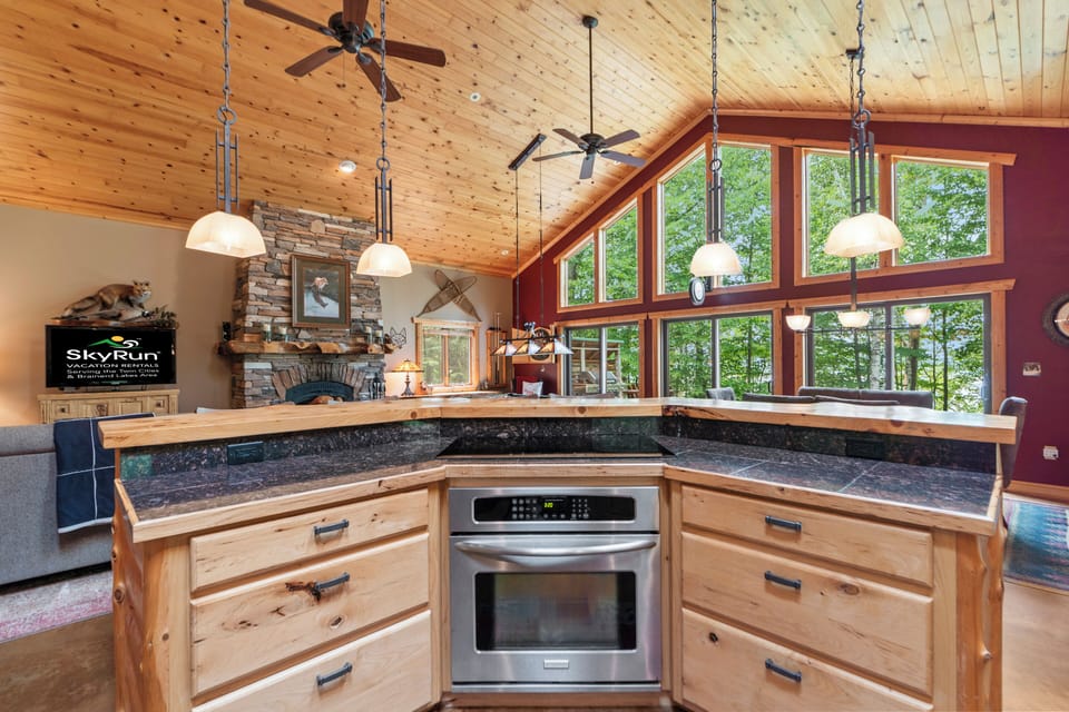 Cook your favorite meals in a warm, wood-wrapped kitchen with high ceilings and natural light streaming through forest views. The open layout keeps you connected to everyone during your stay.