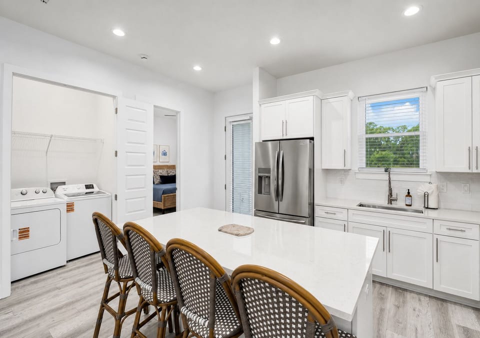 1st Floor - Fully stocked kitchen with quartz countertops, stainless steel appliances, generous prep space, and island seating for 4, with the full-size laundry room conveniently nearby.