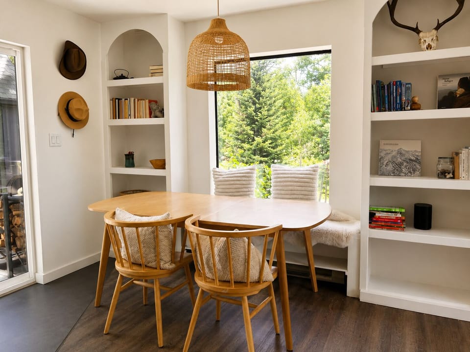 Bright dining nook with window bench, built-ins, and peaceful forest views