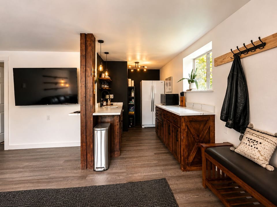 Modern rustic kitchenette with TV, ample storage, and inviting entry bench