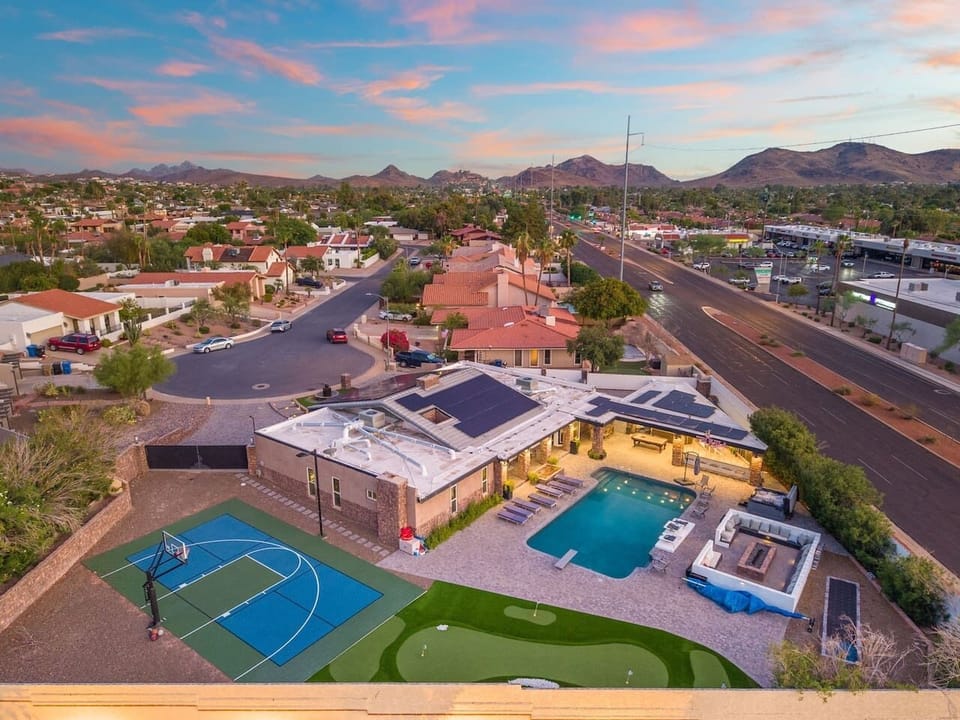 A sunset aerial captures the pool, putting green, and sport court all in one frame.