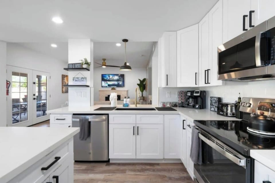 Modern kitchen with stainless steel appliances, white cabinetry, and open concept flow to living areas.