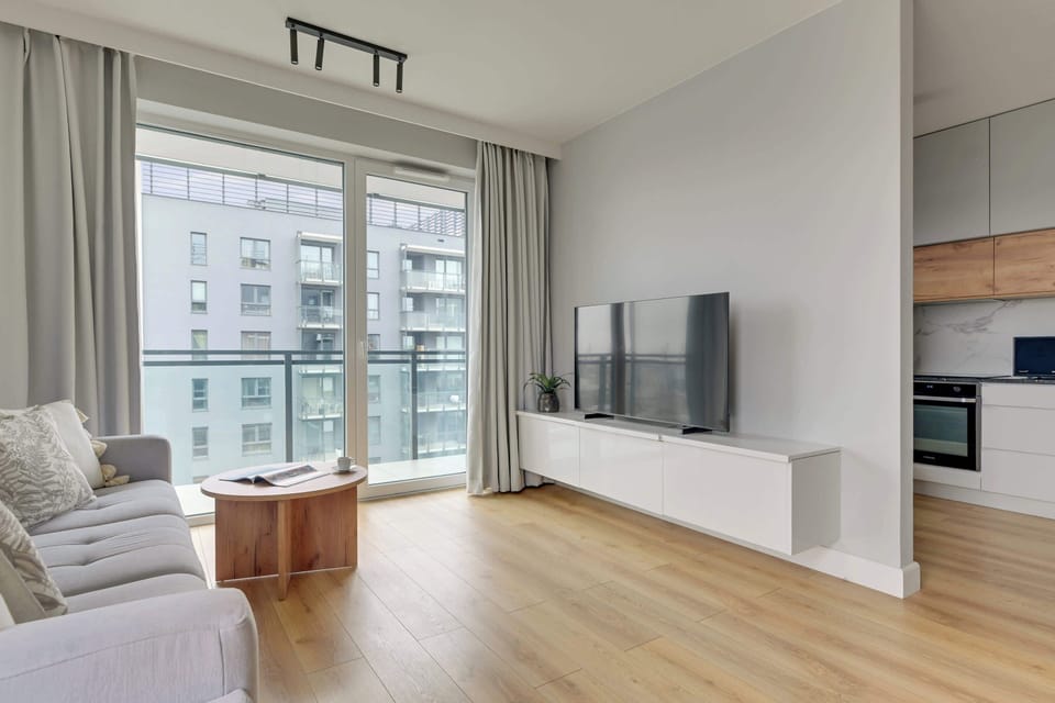 Przestronny salon wyposażony jest w dużą, rozkładaną sofę zapewniającą dodatkowe miejsce do spania oraz telewizor Smart TV z dostępem do kanałów kablowych. 