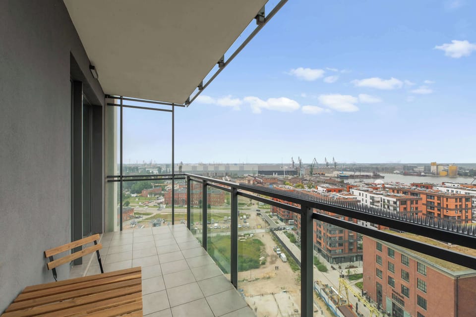 Z salonu można wyjść na umeblowany balkon wyposażony w stół i miejsca do siedzenia. Z 15. piętra rozpościera się panoramiczny widok na Gdańsk, Stare Miasto, tereny stoczniowo-portowe oraz rzekę. 