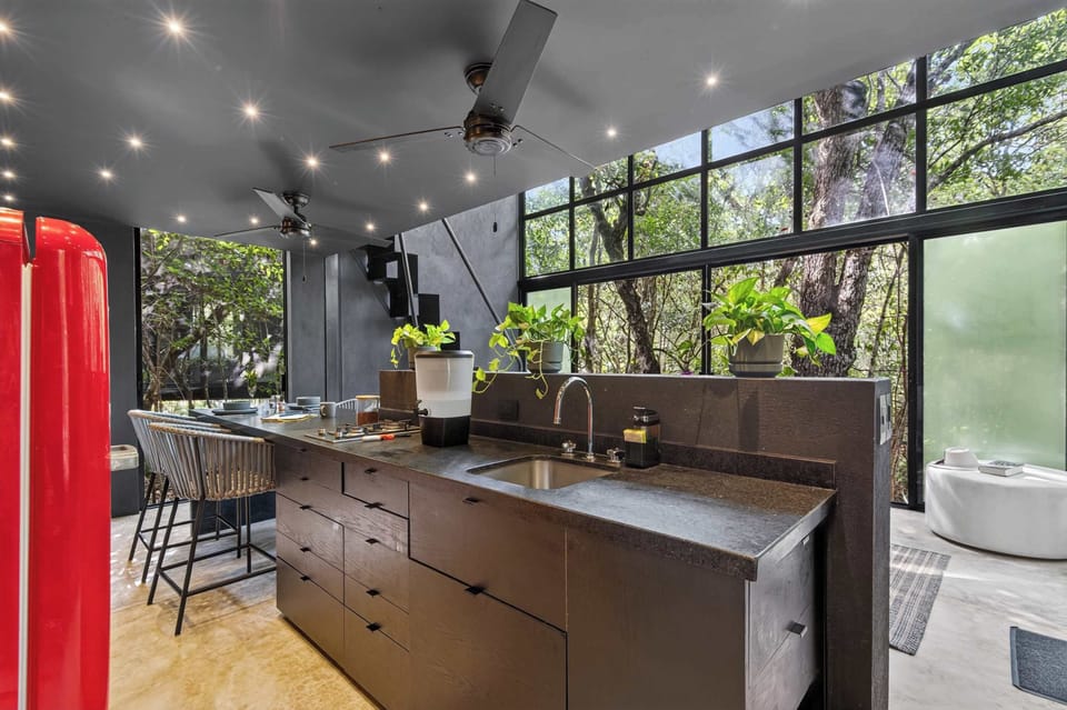 The full kitchen: black granite counter, vintage Smeg refrigerator, bamboo accent wall, and jungle views from every angle