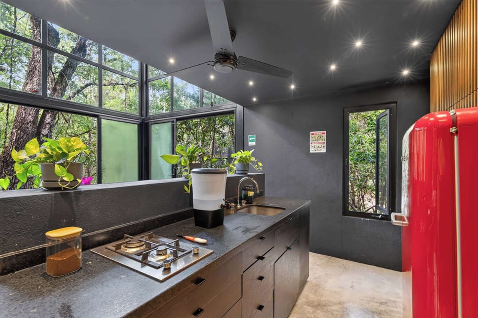 The full kitchen: black granite counter, Teka stove, drinkable water, and jungle views