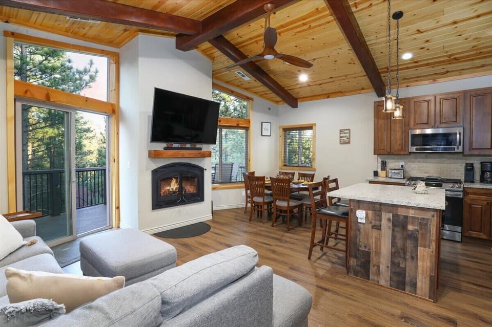 Vaulted great room with wood-burning fireplace, forest views and an open kitchen.