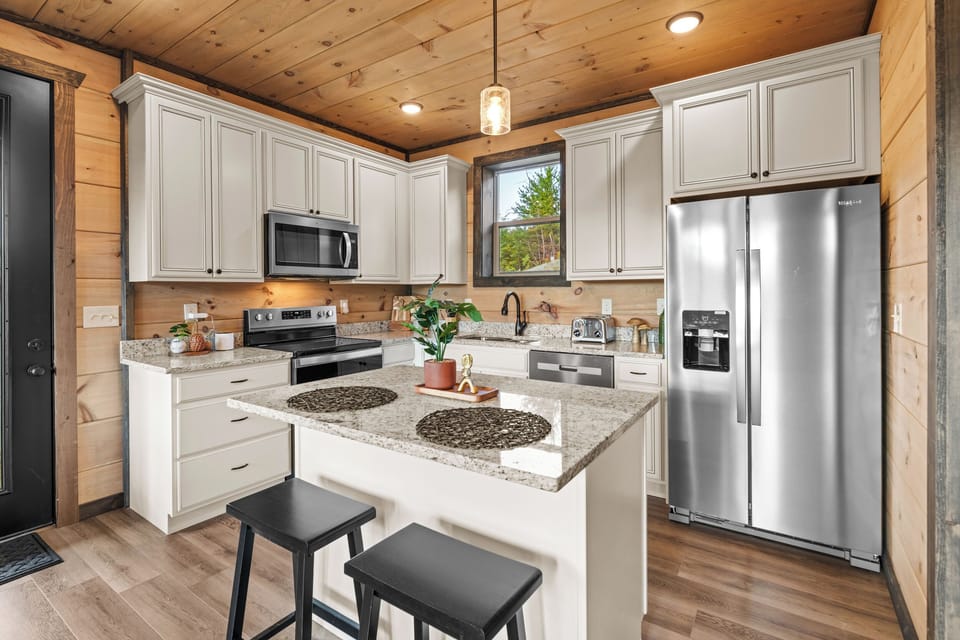 Modern cabin kitchen with granite island, seating, and stainless appliances