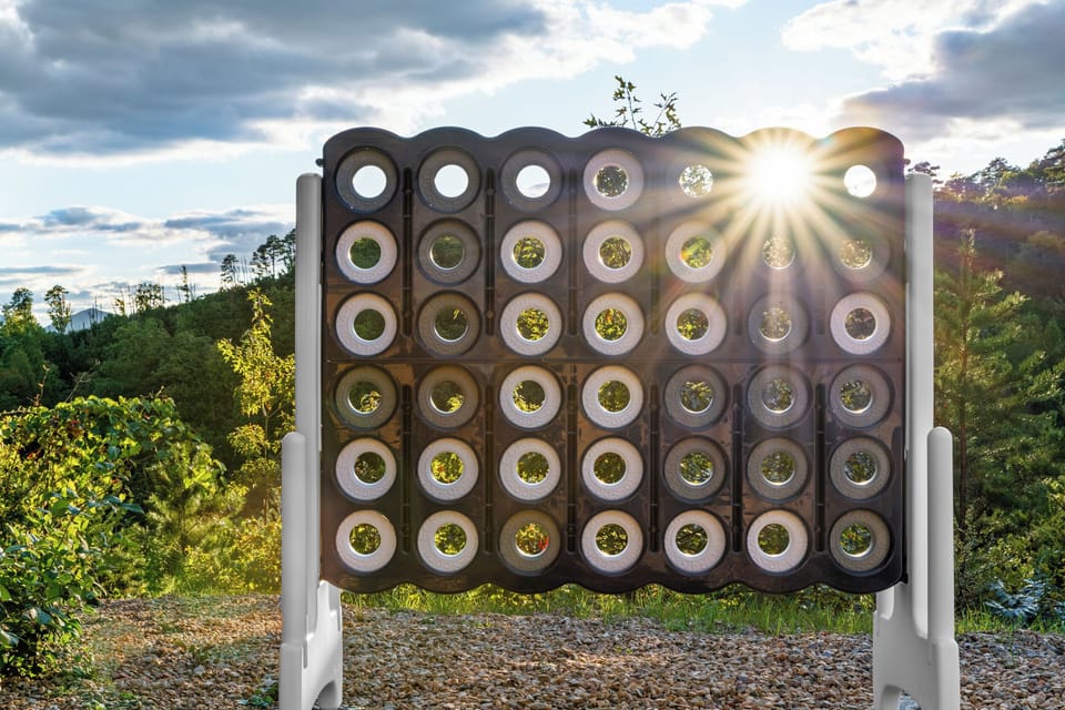 Scenic outdoor Connect Four with sunlit mountain views