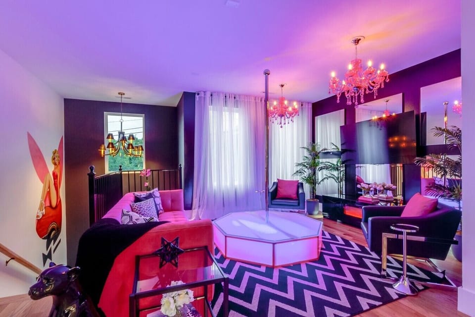 Unforgettable group lounge featuring luxury tufted armchairs, a statement chandelier, and geometric rug design.