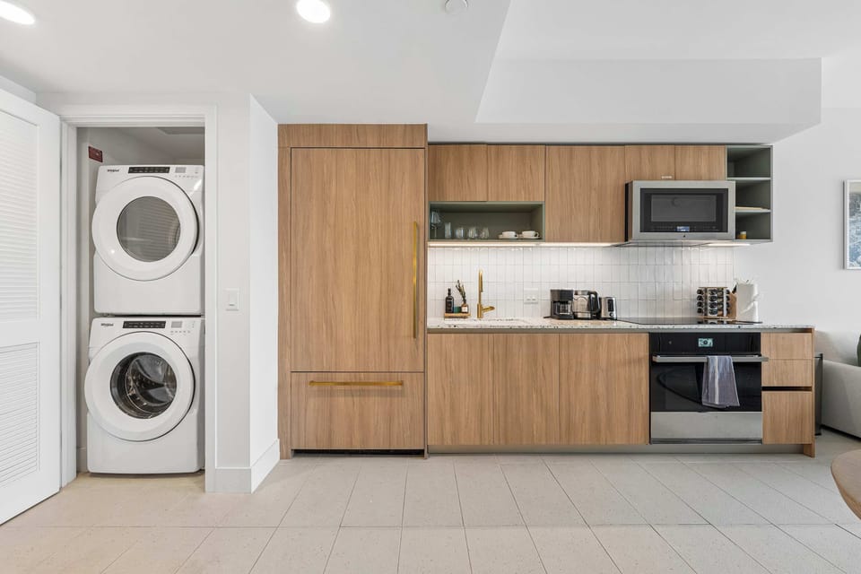 Fully equipped kitchen featuring wood cabinetry and an in-unit stacked washer and dryer for your convenience