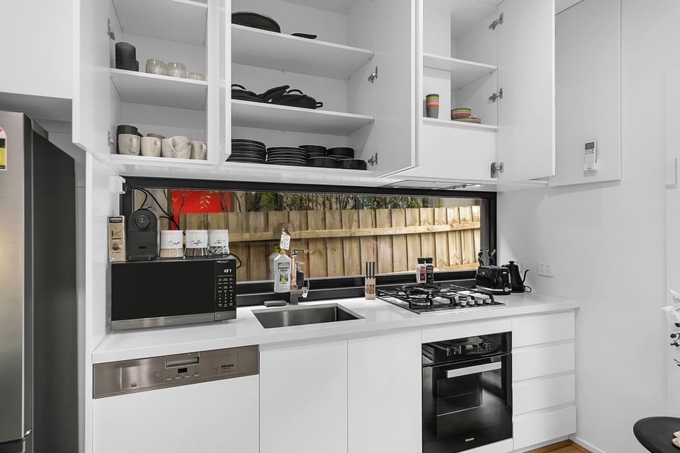 Bright modern kitchen with gas cooktop, coffee machine, and garden-view window