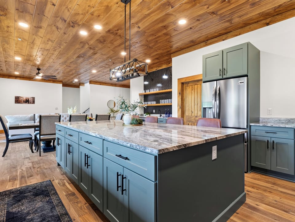 Wide-angle view of the gourmet kitchen featuring an expansive blue-green island with marble countertops.