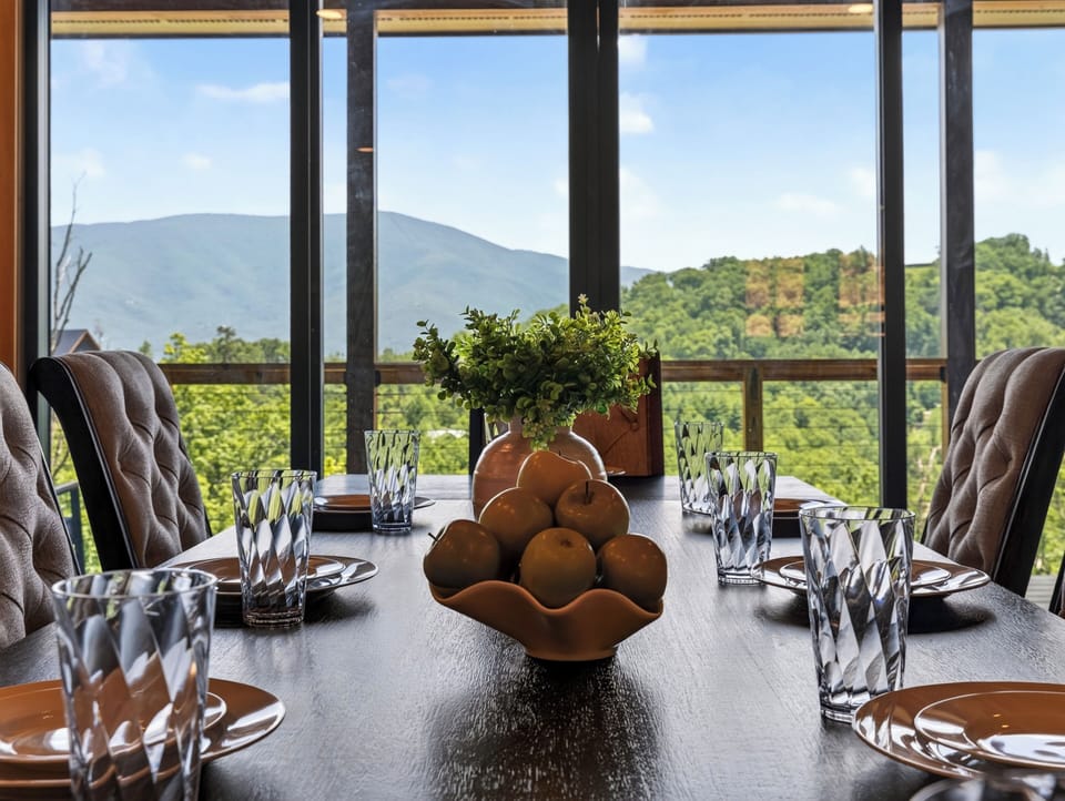 Close-up of the dining table set for dinner, showcasing a mountain view framed through floor-to-ceiling windows.