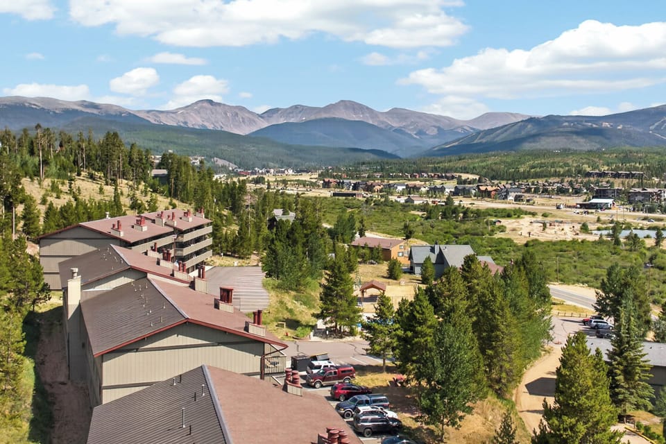 An alpine mountain community nestled among evergreen forests, with dramatic peaks rising beyond the town's residential neighborhoods and tree-lined streets.