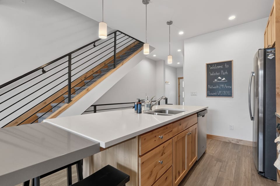 Your modern mountain retreat kitchen awaits with gleaming countertops, stainless appliances, and warm wood accents—perfect for gathering with loved ones after a day of adventure.
