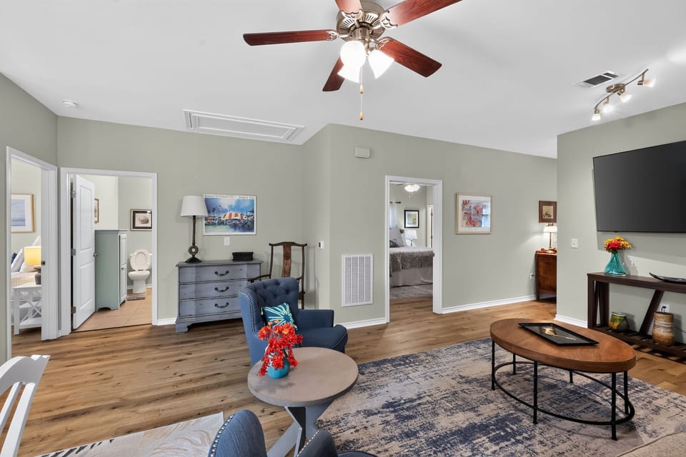 Living area with wood-style floors, cozy seating, and a wall-mounted television.