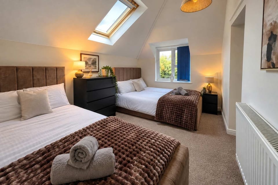 Bedroom : Two double beds, sloped ceiling skylight, and dark wooden chest of drawers , wake up to bright natural light in this cozy top-floor retreat.
