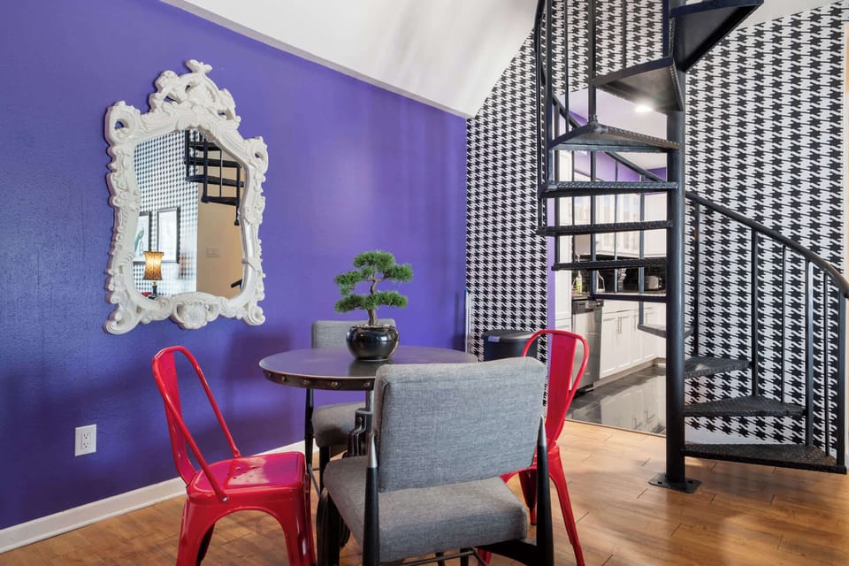 Chic dining area with bold colors and a stylish spiral staircase, perfect for intimate meals.