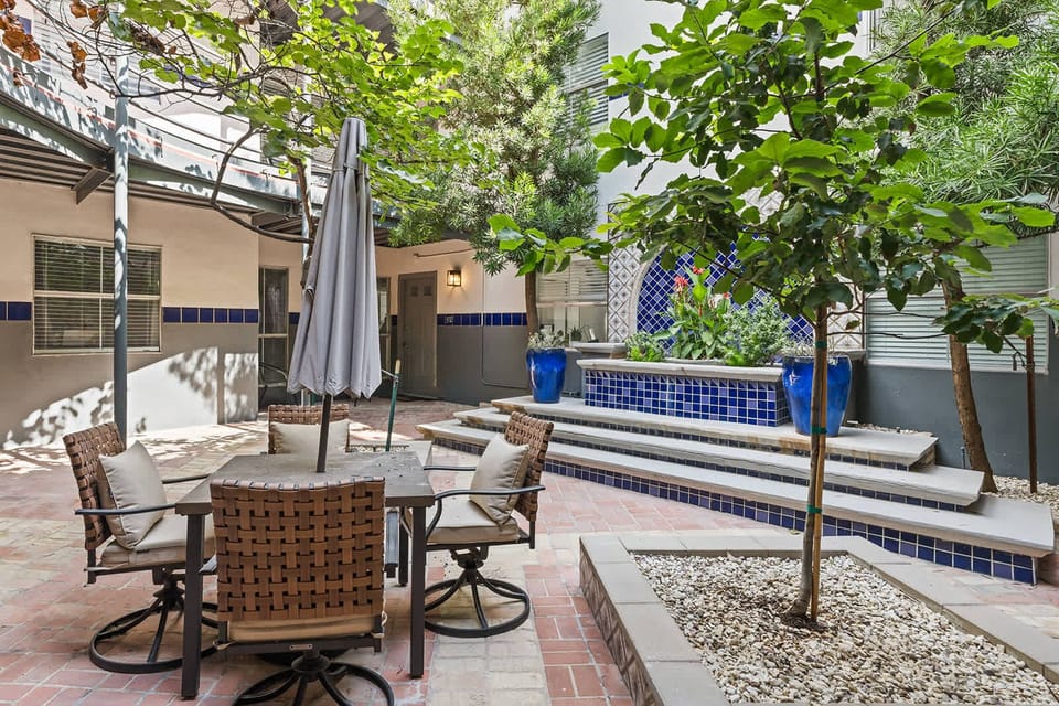 Relax in this charming outdoor patio with lush greenery and stylish seating, perfect for a peaceful retreat.
