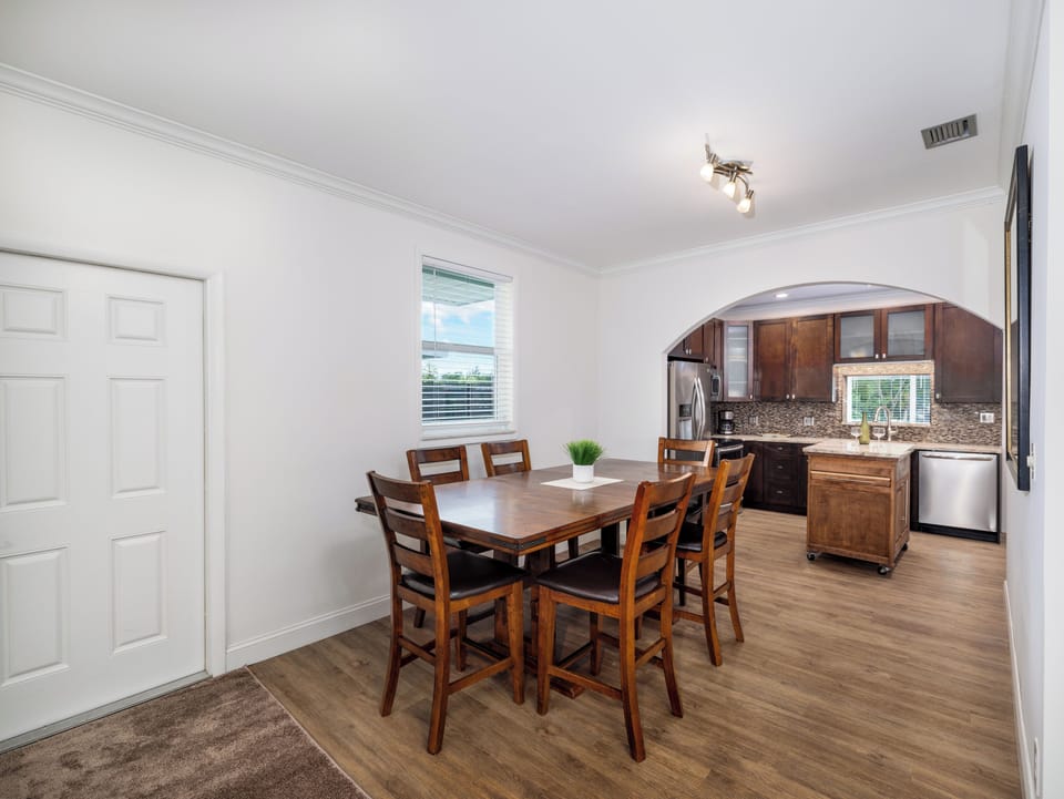 Gather for memorable meals in this inviting dining space, featuring a large wooden table, bright natural light, and the perfect backdrop for your getaway