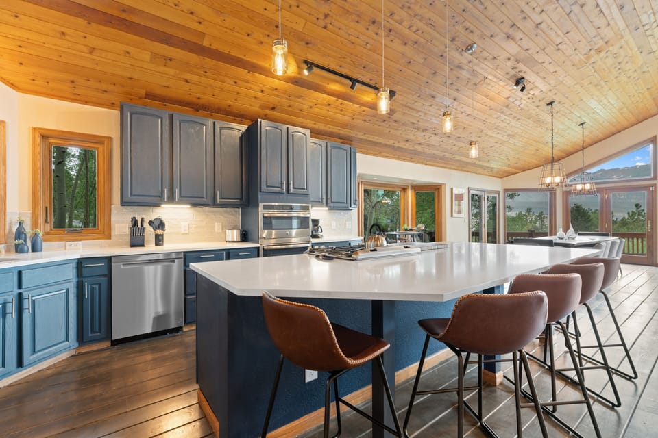 Spacious modern kitchen with sleek quartz countertops, stainless appliances, and warm wood ceiling creates a welcoming heart of the home where you'll love cooking and gathering with friends and family.