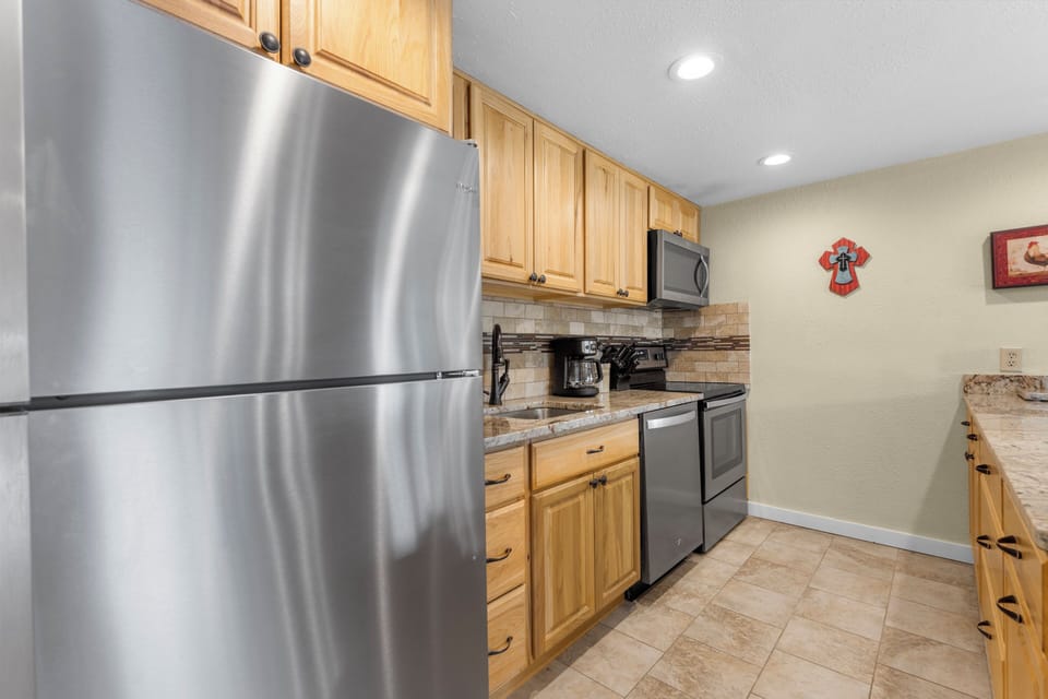 Your fully equipped kitchen features stainless steel appliances, granite countertops, and warm wood cabinetry—perfect for preparing everything from quick breakfasts to home-cooked meals during your stay.