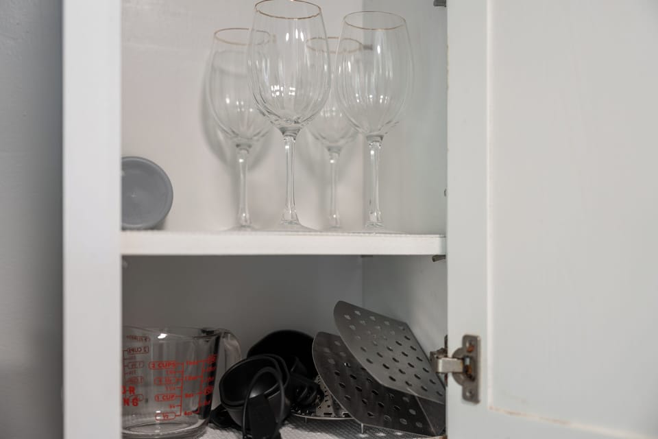 Stocked kitchen cabinet with wine glasses and handy cooking essentials