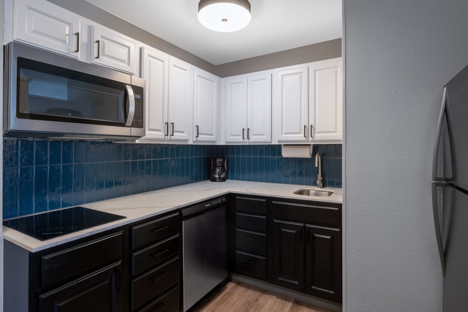 Kitchen with white and dark cabinetry and full appliances.