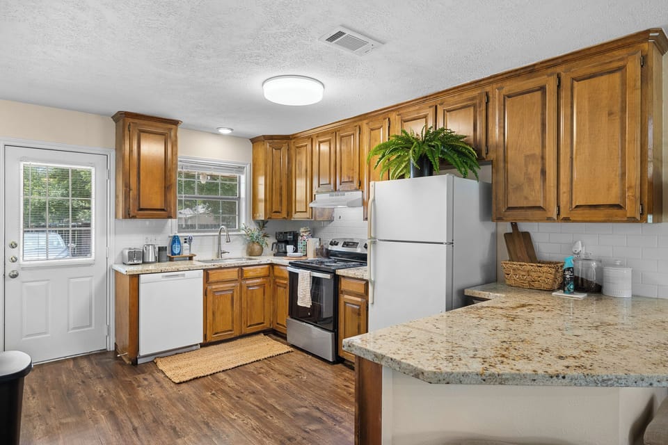 Bright kitchen with granite counters, full appliances, and warm wood cabinets