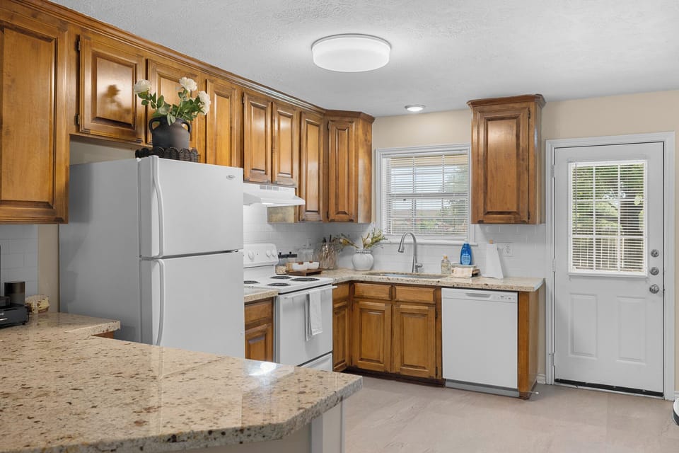 Bright kitchen with granite counters, warm wood cabinets, and outdoor access