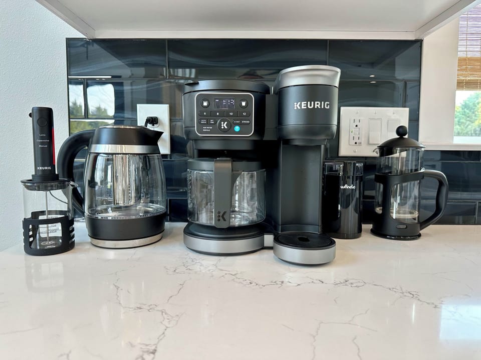 Keurig, drip carafe, French press and an electric kettle — the coffee bar is up before you are.