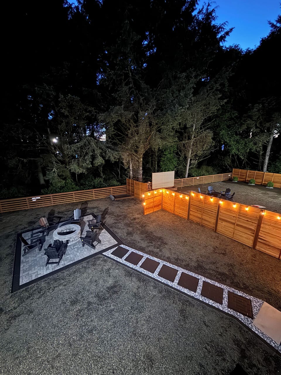 Watch the string lights flick on at dusk — the fire pit keeps glowing long after sunset, and the lit paver path walks you right back to the door.