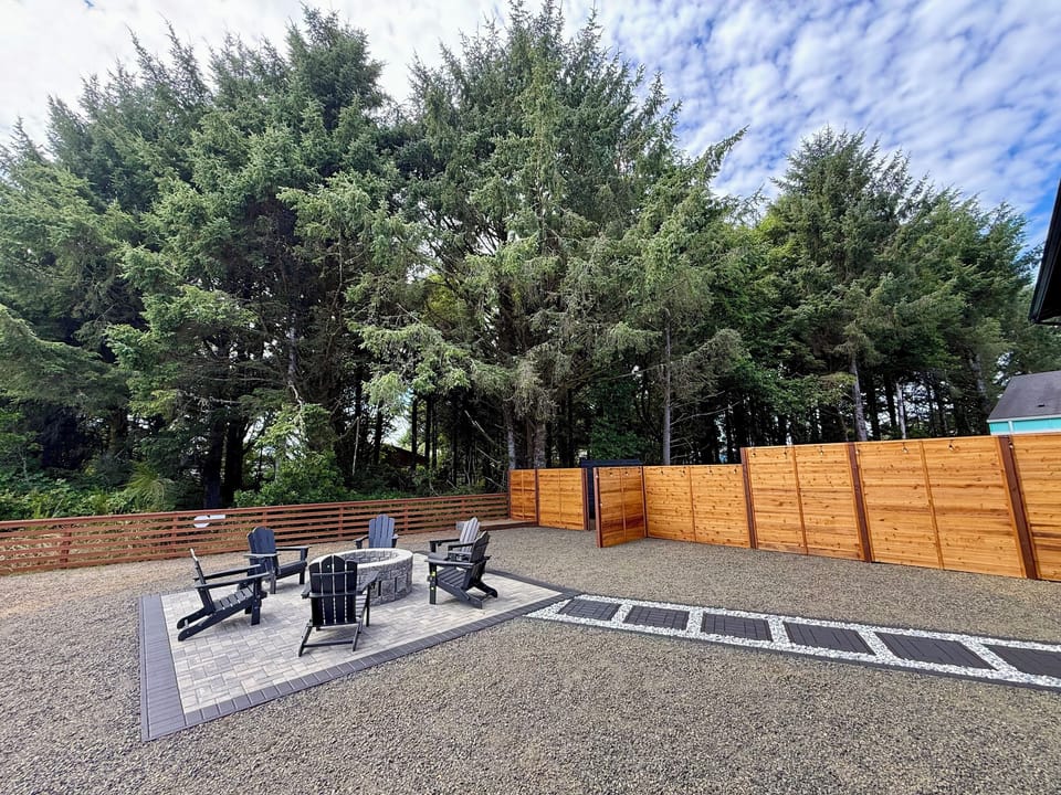 Pull up one of the six Adirondack chairs around the fire pit — the paver patio out back is where the day winds down, tucked in behind the cedar fence.