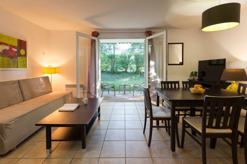 A pull-out sofa bed in the living area adds flexibility for groups of five — fold it away and the room becomes a bright, open space looking out onto the terrace.