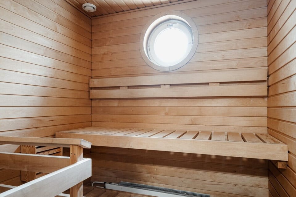 Sauna benches beneath a round window, a quiet place to relax in the evening.