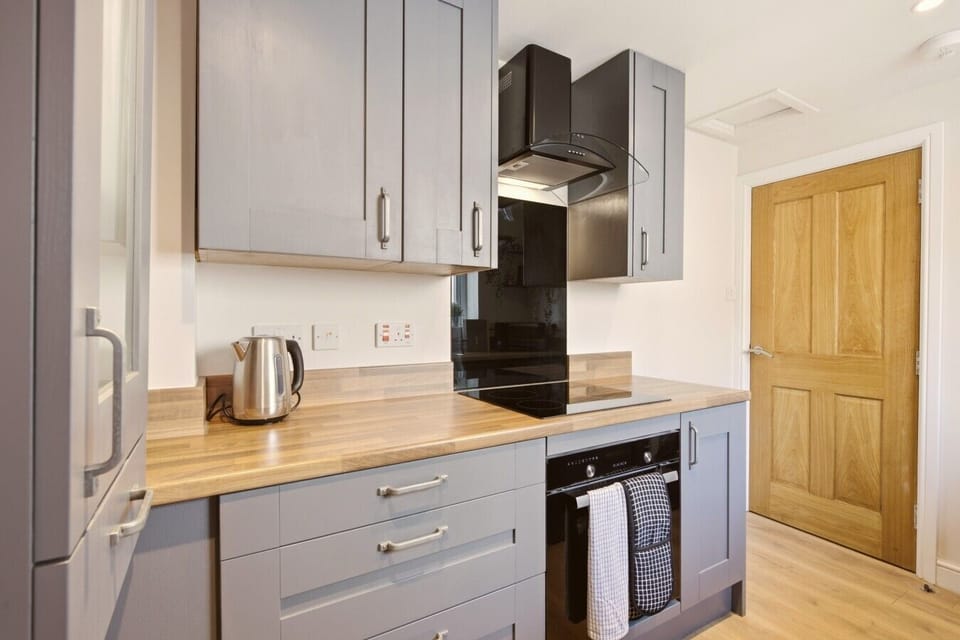 Modern kitchen with grey cabinetry and black glass splashback.