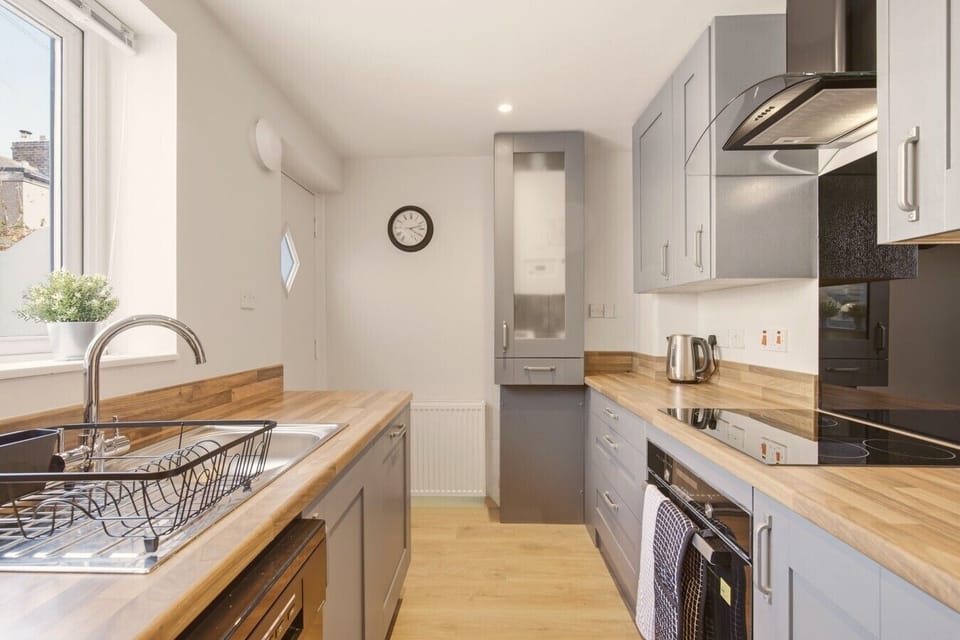 Grey kitchen with wooden worktops, integrated appliances and sink
