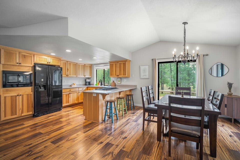 Your open-concept kitchen and dining space welcomes you with warm wood tones, modern appliances, and bright natural light streaming through garden views—perfect for gathering and creating memories together.
