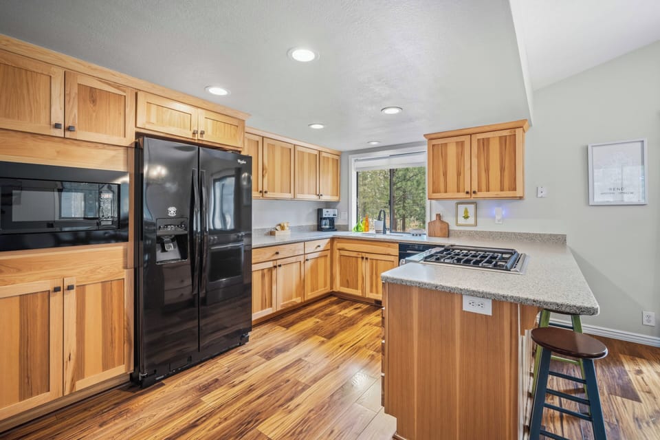 Your fully equipped kitchen features warm wood cabinetry, modern appliances, and a convenient peninsula with seating—perfect for preparing your favorite meals and gathering with loved ones.