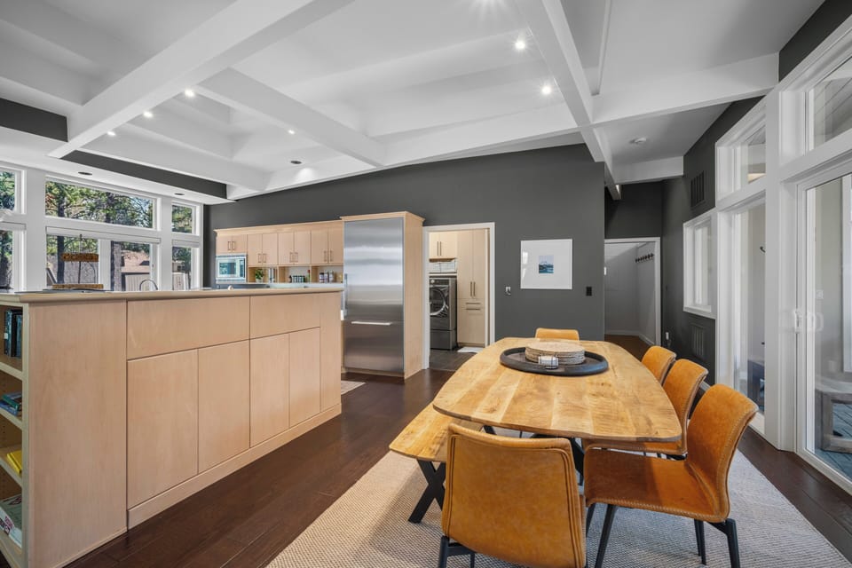 Gather around the warm wood dining table beneath elegant coffered ceilings, where your group can share meals prepared in the modern, fully equipped kitchen with stainless steel appliances.