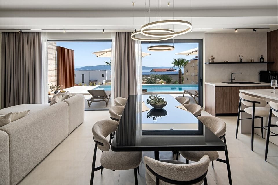 As you enter the ground floor, you’ll find an inviting living area that features a dining space for 8, a comfortable sofa, and a TV, all with breathtaking sea views